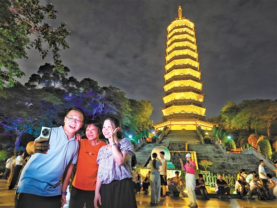 成功登頂?shù)氖忻衲贸鍪謾C(jī)與龍光塔合影。