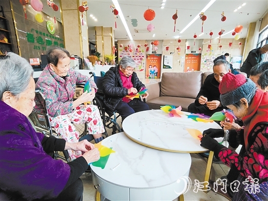 老人們圍坐在桌前，專注地制作小風(fēng)車。