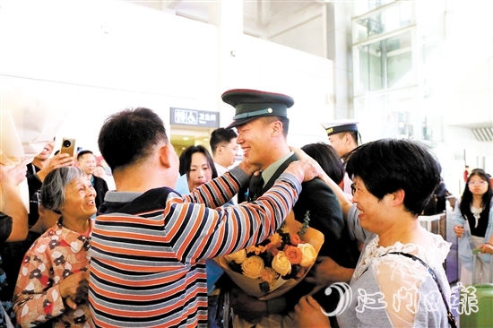 身著軍裝的返鄉(xiāng)退役士兵逐一出站，迎接他們的是鮮花與擁抱。