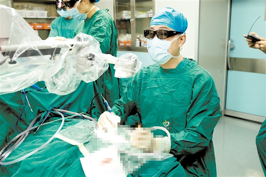 術(shù)中，醫(yī)生查看顯示屏，為患者植入人工耳蝸。