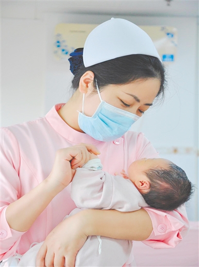 這是一雙托起生命的手。江門市中心醫(yī)院愛嬰?yún)^(qū)主管護(hù)師湯玲玲正在安撫哭鬧的寶寶。她一手環(huán)住襁褓，一手牽起寶寶的小手，動(dòng)作舒緩而溫柔。在這里，生命的啼哭與溫柔的守護(hù)相遇，匯聚成世間至暖的力量。（林錦棠