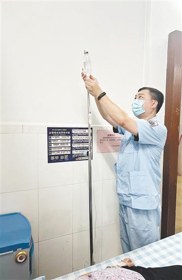 吳益浩核對藥液、為患者調(diào)整輸液流速。