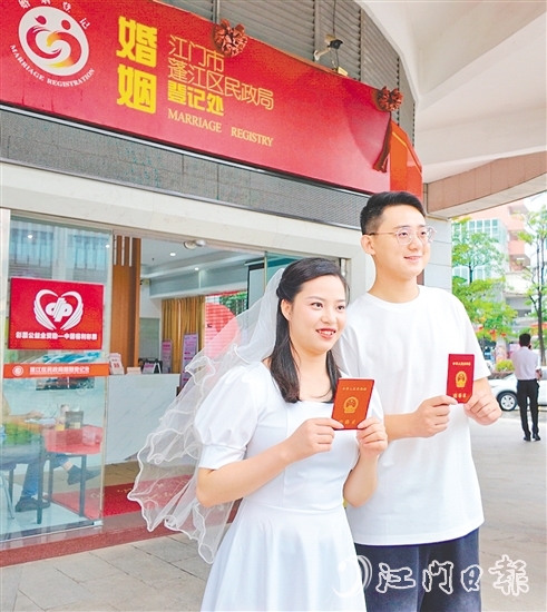 一對(duì)新人在蓬江區(qū)民政局婚姻登記處門口合影留念。