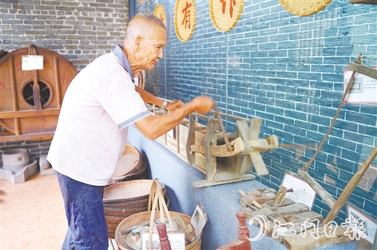 新華村打造農(nóng)耕文化展館，留住鄉(xiāng)村記憶。圖為村中老人向記者介紹農(nóng)具。