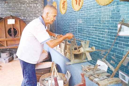 新華村打造農(nóng)耕文化展館，留住鄉(xiāng)村記憶。圖為村中老人向記者介紹農(nóng)具。