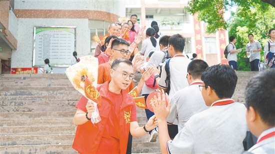 在景賢學(xué)校考點(diǎn)，老師們手持向日葵和小紅旗為考生加油。