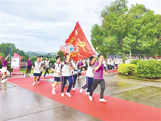在臺(tái)山市武溪中學(xué)，老師揮舞著“中考加油”的紅旗為考生加油助威。