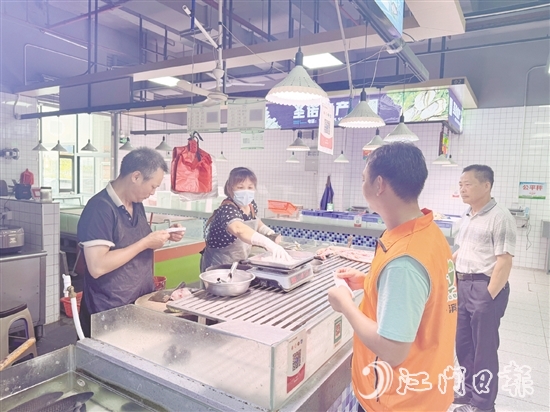 買菜易的平臺接單員李叔（橙色馬甲）正在魚攤旁等待取單。