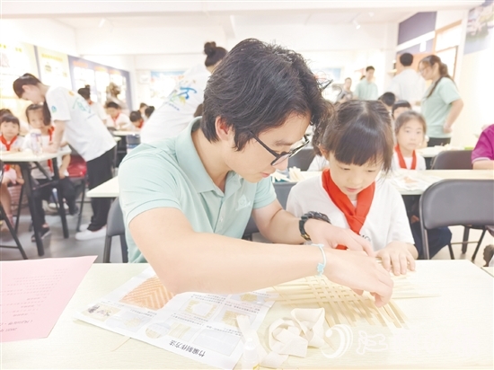 學(xué)生志愿者耐心教導(dǎo)孩子制作手工。