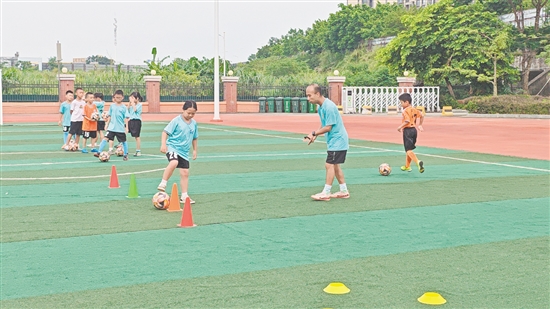 學(xué)生在教練的指導(dǎo)下學(xué)習(xí)足球技巧。