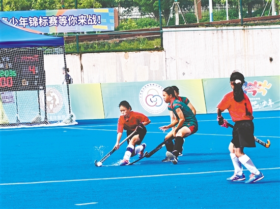 共和鎮(zhèn)中心小學(xué)女子曲棍球隊隊員（紅色隊服）在比賽中頑強拼搏。