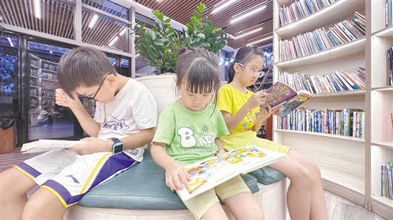 低年級(jí)學(xué)生圍坐在書架旁閱讀繪本。