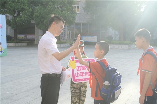 紫茶小學黨委書記譚國池與學生逐一擊掌。
