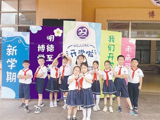 開學首日，農(nóng)林雙朗小學的學生們在學校精心準備的背景板前留影。