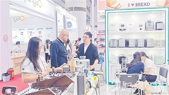 外國客商在一家蓬江區(qū)家電企業(yè)的展區(qū)前洽談合作。任佳燕